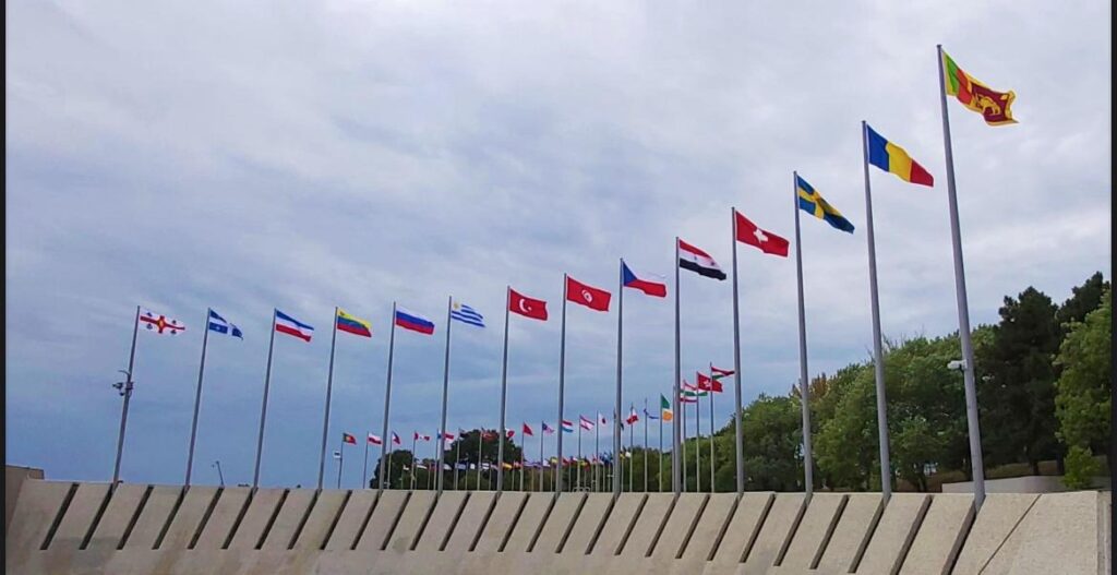 “Row of international flags from different countries displayed on tall flagpoles against a cloudy sky, symbolizing global unity and international relations.” these are country for visa updates we provide