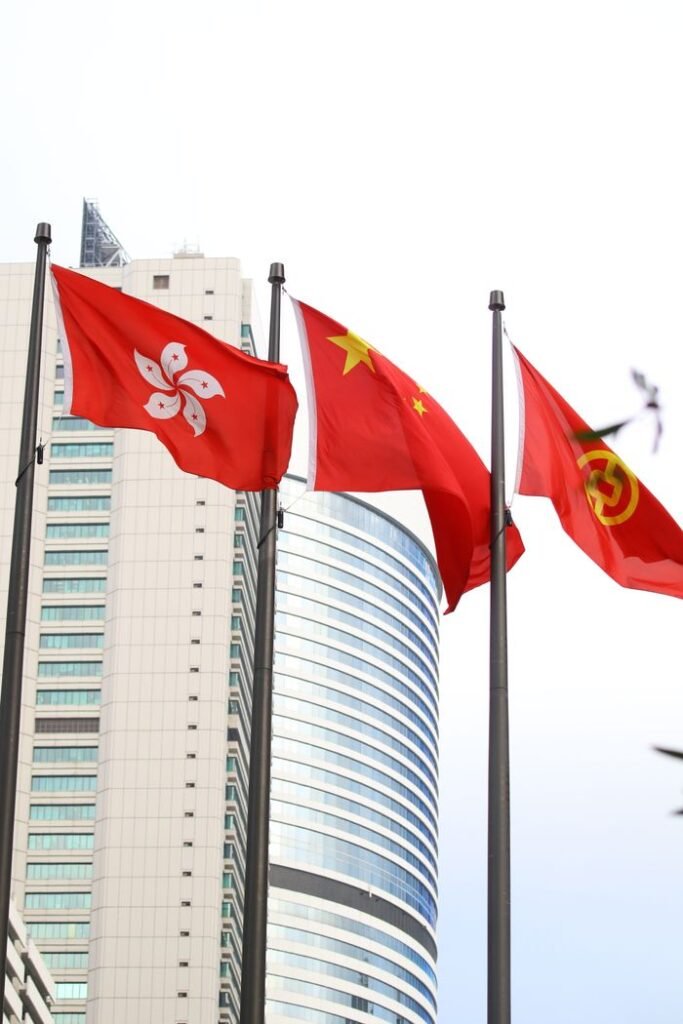 Flags of Hong Kong and China against a modern urban skyline, symbolizing cultural and political ties.
