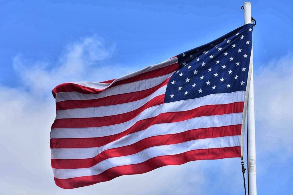 The American flag waving majestically against a vibrant blue sky, symbolizing patriotism and freedom.